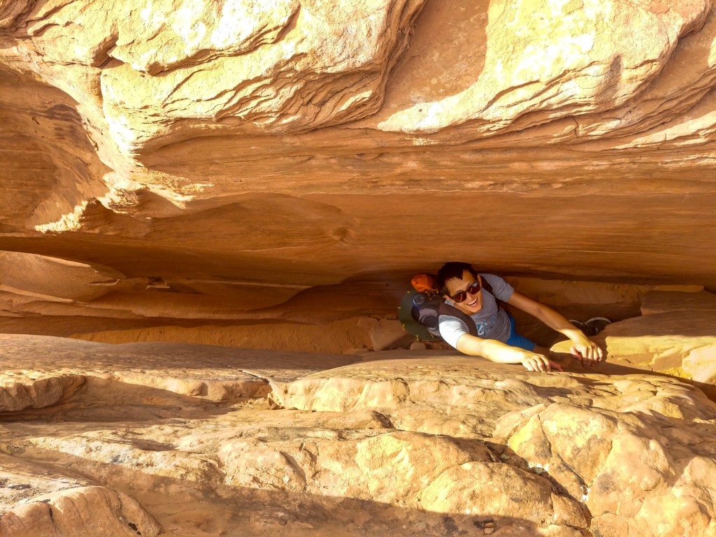 Climber scaling the crack in the wall at the exit of Coyote Gulch Canyon. 